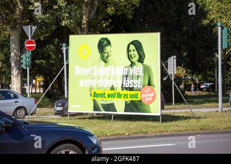 Wiesbaden, Deutschland - 25. August 2021: Wahlkampfplakat der Partei DIE GRÜNEN in der Innenstadt von Wiesbaden, Hessen. Das Bündnis 90/die Grünen, oft einfach nur Grüne genannt (Bündnis 90/die Grünen), ist eine grüne politische Partei in Deutschland und wird von Annalena Baerbock und Robert Habeck angeführt. Deutschland steht am 26. September vor Bundestagswahlen. Einige Verkehrsteilnehmer im Hintergrund Stockfoto