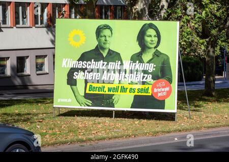 Wiesbaden, Deutschland - 25. August 2021: Wahlkampfplakat der Partei DIE GRÜNEN in der Innenstadt von Wiesbaden, Hessen. Das Bündnis 90/die Grünen, oft einfach nur Grüne genannt (Bündnis 90/die Grünen), ist eine grüne politische Partei in Deutschland und wird von Annalena Baerbock und Robert Habeck angeführt. Deutschland steht am 26. September vor Bundestagswahlen. Einige Verkehrsteilnehmer im Hintergrund Stockfoto