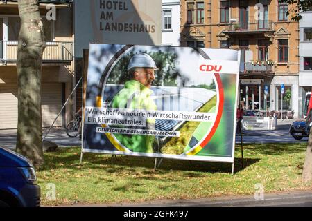 Wiesbaden, Deutschland - 25. August 2021: Wahlkampfplakat der Christlich Demokratische Union (CDU) in der Innenstadt von Wiesbaden, Hessen. Die Christlich-Demokratische Union (CDU) ist eine christdemokratische und liberal-konservative Partei in Deutschland und wird von Armin Laschet angeführt. Deutschland steht am 26. September vor Bundestagswahlen. Einige Verkehrsteilnehmer im Hintergrund Stockfoto