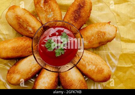 Gebratene Brötchen mit Tomatensauce, serviert in Glasteller auf goldenem Hintergrund Stockfoto