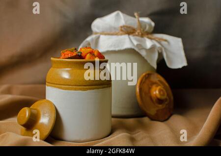 Hausgemachte rohe Mangobeize in einem traditionellen Keramikglas auf braunem Hintergrund Stockfoto