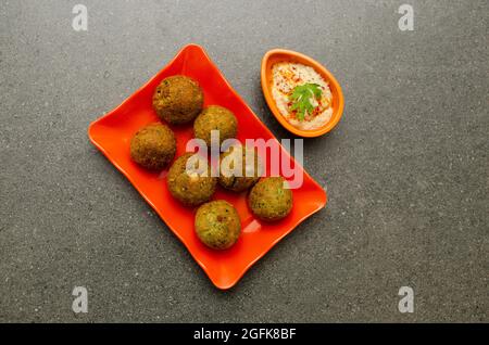 Traditionelles ägyptisches Gericht Falafel mit Hummus serviert in orangefarbener Platte auf grauem Hintergrund Stockfoto