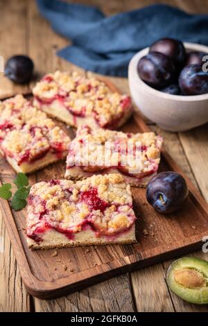 Saftige Pflaumenkuchen-Scheiben mit knuspriger Streusel-Belag auf rustikalem Holzhintergrund Stockfoto