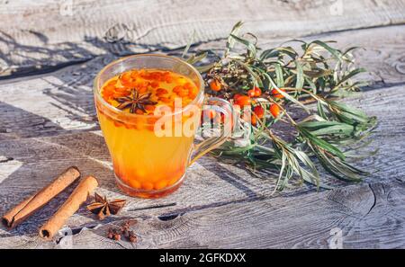 Heißer Vitamin Sanddorntee in eine Tasse, steht auf einem alten Holztisch. Entspannung und Kräutermedizin, Anti-Kalk, Grippesaison Stockfoto