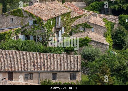 FRANKREICH, LUBERON, VAUCLUSE, 84, OPPEDE-LE-VIEUX, SCHÖNES KLEINES DORF AUF EINEM FELSIGEN AUSBISS ÜBERWUCHERT VEGETATION MIT EINER HERRLICHEN KULISSE GEBAUT, EIN Stockfoto