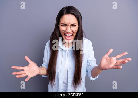 Foto von aggressiven wütend reifen Frau tragen formelle Hemd Brille aufsteigende Arme isoliert graue Farbe Hintergrund Stockfoto