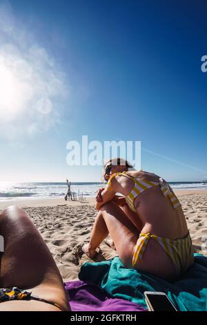 Zwei Frauen sitzen am Strand gegen das Meer Stockfoto