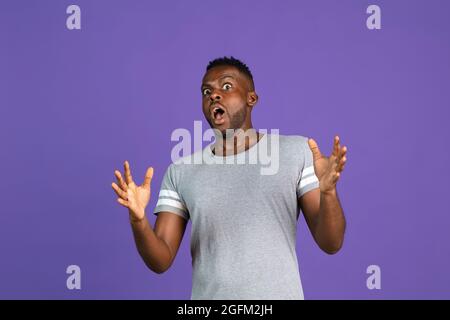 afroamerikanischer junger Mann auf purpurfarbenem Studiohintergrund. Konzept der menschlichen Emotionen, Gesichtsausdruck, Jugend, Gefühle, Anzeige. Stockfoto
