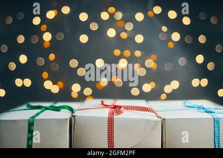 Nahaufnahme von Geschenken auf hellem Bokeh-Hintergrund. Weiße Boxen mit bunten Bändern stehen in Reihe. Komposition zu Neujahr oder Weihnachten. Festliches Stillleben. Stockfoto