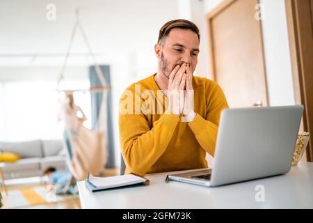 Verärgert junger Mann zählt Familie Haushalt auf Laptop Stockfoto