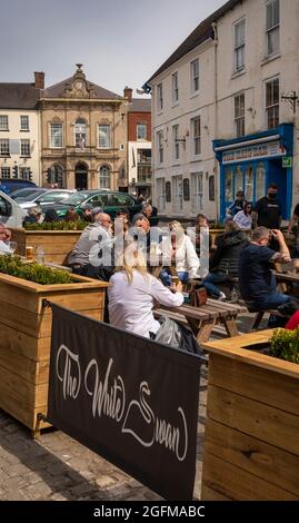 Großbritannien, England, Derbyshire, Ashbourne, Market Place, Gäste des Pubs Victoria Square, White Swan, die bei Sonnenschein draußen sind Stockfoto