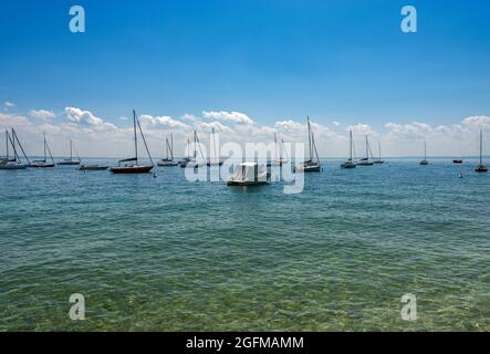 Schöne Bucht mit Segelbooten vor der kleinen Stadt Garda, Ferienort an der Küste des Gardasees, vertäut. Verona, Venetien, Italien. Stockfoto