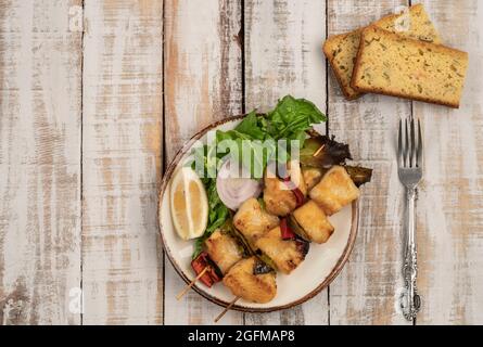 Schiefe Seezunge serviert mit Salat und Maisbrot auf einem Holztisch Stockfoto