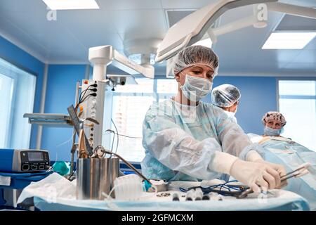 Ein Team von Chirurgen kämpft um das Leben und führt eine komplexe Operation in einem modernen Operationssaal durch. Stockfoto