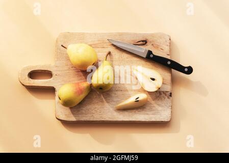 Frische reife Birnen und Messer auf Holzschneidebrett. Draufsicht, flach liegend. Stockfoto