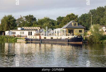 Boote und Häuser liegen am Ufer der themse bei Laleham in surrey Stockfoto