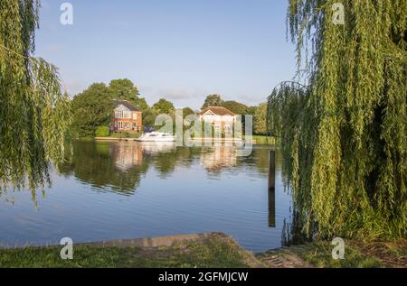 Boote und Häuser liegen am Ufer der themse bei Laleham in surrey Stockfoto