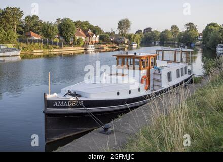 Boote und Häuser liegen am Ufer der themse bei Laleham in surrey Stockfoto