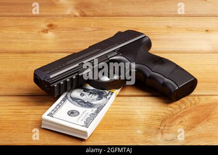 Schwarze Pistole und Geldscheine auf Holztisch. Stockfoto