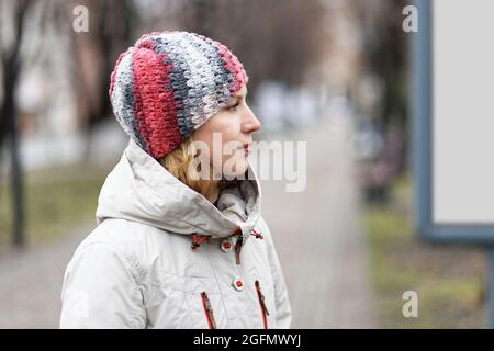 Porträt im Profil einer jungen Frau in einer leichten Herbstjacke. Unscharfer Hintergrund. Stockfoto