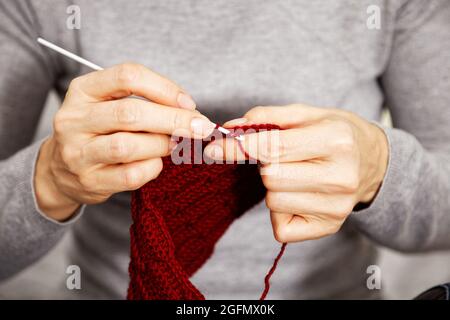 Nahaufnahme Womans Hände Stricken rot burgunderrot Wolle Garn. Geringer Fokus. Stockfoto