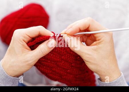 Nahaufnahme Womans Hände Stricken rot burgunderrot Wolle Garn. Ansicht von oben. Geringer Fokus. Stockfoto