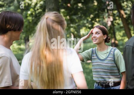 Lächelndes Teenager-Mädchen, das in der Nähe verschwommener interrassischer Freunde im Freien Stockfoto