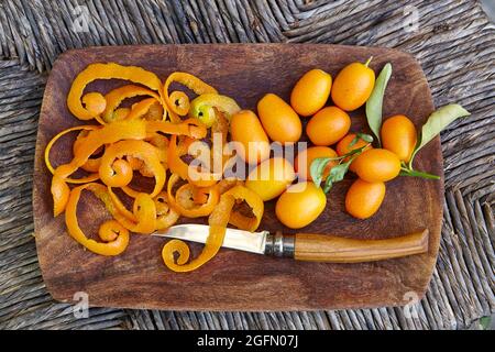 Präsentation von frisch gepflückten Kumquats, Kumquatschälen und einem Fruchtmesser in einer Holzschüssel Stockfoto