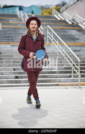 Fröhlicher Brünette Mann hält Djembe in den Händen Stockfoto