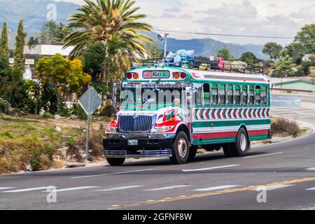 INTERAMERICANA, GUATEMALA - 22. MÄRZ 2016: Farbenfroher Hühnerbus, ehemaliger US-Schulbus, fährt auf der Interamericana-Autobahn in Guatemala. Stockfoto