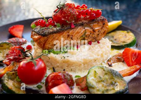 Köstliches Risotto mit gebackenem gegrilltem Lachssteak mit Beeren und Gemüse. Mediterrane Küche Stockfoto