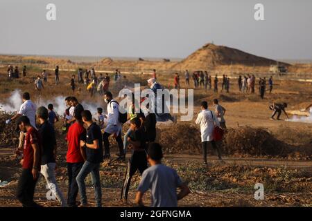 Gaza-Streifen. August 2021. Palästinensische Demonstranten laufen von Tränengas, das von israelischen Sicherheitskräften während eines Protestes entlang des Grenzzauns östlich von Khan Yunis im südlichen Gazastreifen abgefeuert wurde, um die israelische Blockade des palästinensischen Sektors anzuprangern. Stockfoto