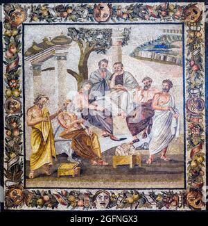 Platons Akademie Mosaikemblema in opus vermiculatum aus polychromen Tesserae. Das Mosaik zeigt eine Gruppe von Philosophen, erkennbar an ihren Kleidern und den Symbolen ihrer Wissenschaft, die unter einem Baum, zwischen einer Votivsäule und einem heiligen Tor mit Vasen, tief diskutiert werden. In der Ferne befindet sich eine ummauerte Stadt. Die Szene ist von einem Festoon aus Blättern und Früchten umgeben, geschmückt mit Bändern und Comic-Masken. Pompeji, Villa von T. Siminius Stephanus Anfang des 1. Jahrhunderts v. Chr. Stockfoto