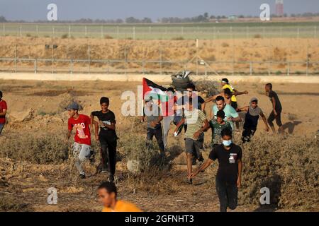 Gaza-Streifen. August 2021. Palästinensische Demonstranten laufen von Tränengas, das von israelischen Sicherheitskräften während eines Protestes entlang des Grenzzauns östlich von Khan Yunis im südlichen Gazastreifen abgefeuert wurde, um die israelische Blockade des palästinensischen Sektors anzuprangern. Stockfoto