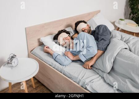 gay paar in Augenmasken Umarmung während schlafen im Bett Stockfoto