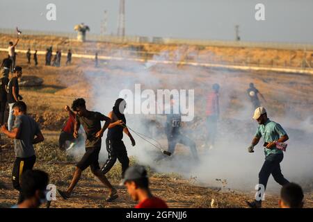 Gaza-Streifen. August 2021. Palästinensische Demonstranten laufen von Tränengas, das von israelischen Sicherheitskräften während eines Protestes entlang des Grenzzauns östlich von Khan Yunis im südlichen Gazastreifen abgefeuert wurde, um die israelische Blockade des palästinensischen Sektors anzuprangern. Stockfoto