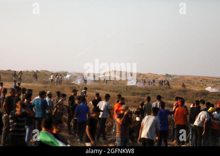 Gaza-Streifen. August 2021. Palästinensische Demonstranten laufen von Tränengas, das von israelischen Sicherheitskräften während eines Protestes entlang des Grenzzauns östlich von Khan Yunis im südlichen Gazastreifen abgefeuert wurde, um die israelische Blockade des palästinensischen Sektors anzuprangern. Stockfoto