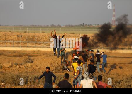 Gaza-Streifen. August 2021. Palästinensische Demonstranten laufen von Tränengas, das von israelischen Sicherheitskräften während eines Protestes entlang des Grenzzauns östlich von Khan Yunis im südlichen Gazastreifen abgefeuert wurde, um die israelische Blockade des palästinensischen Sektors anzuprangern. Stockfoto