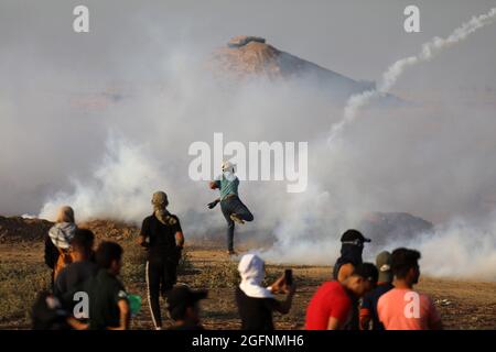 Gaza-Streifen. August 2021. Palästinensische Demonstranten laufen von Tränengas, das von israelischen Sicherheitskräften während eines Protestes entlang des Grenzzauns östlich von Khan Yunis im südlichen Gazastreifen abgefeuert wurde, um die israelische Blockade des palästinensischen Sektors anzuprangern. Stockfoto