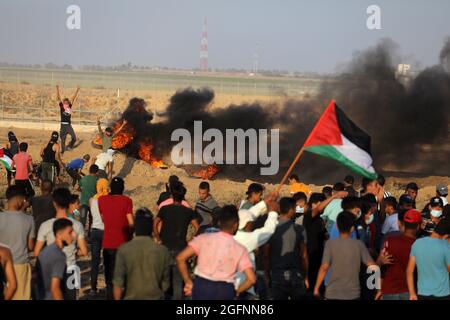Gaza-Streifen. August 2021. Palästinensische Demonstranten laufen von Tränengas, das von israelischen Sicherheitskräften während eines Protestes entlang des Grenzzauns östlich von Khan Yunis im südlichen Gazastreifen abgefeuert wurde, um die israelische Blockade des palästinensischen Sektors anzuprangern. Stockfoto
