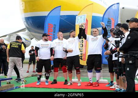 Non Exclusive: HOSTOMEL, UKRAINE - 26. AUGUST 2021 - ukrainische starke Männer feiern den nationalen Rekord für das Ziehen der Antonov an-225 MRT Stockfoto