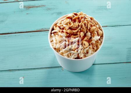 Spezialität Deutsches Vanille-Spaghetti-Eis mit Haselnüssen und Karamellsirup von oben nach unten auf blauem Holz mit Copyspace für Menüwerbung Stockfoto