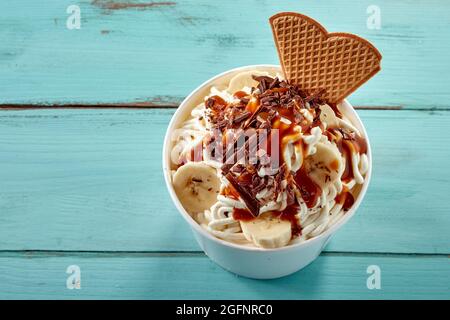 Deutsche Vanillespaghetti-Eis mit Schokoladenflocken, Karamellsauce und frisch geschnittener Banane, serviert mit einem Waffel in einer Wanne, die von oben nach unten für m betrachtet wird Stockfoto