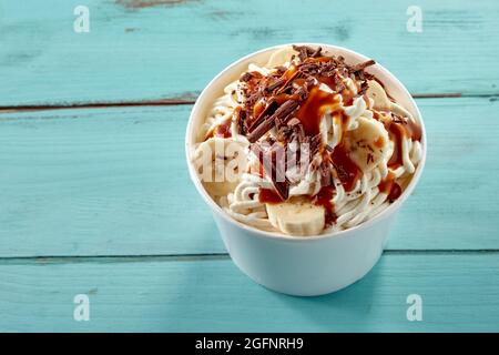 Leckere Vanilleeis-Spaghetti-Sundae mit Schokoladenflocken, frisch geschnittener Banane und Karamellsauce, die von oben nach unten für die Werbung auf der Speisekarte angezeigt werden Stockfoto