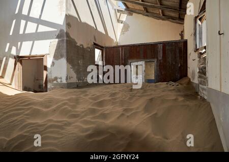 Die Natur hat in einem verlassenen Haus in Kolmanskop, Namibia, Zimmer mit Wüstensand zurückgewonnen. Stockfoto