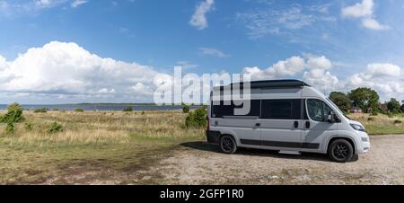 Ohessaare, Estland - 15. August 2021: Grauer Wohnmobil, der auf einem Schotterplatz neben der Ozeanpanorama-Landschaft geparkt ist Stockfoto