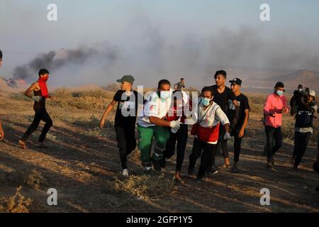 Gaza-Streifen. August 2021. Palästinensische Demonstranten laufen von Tränengas, das von israelischen Sicherheitskräften während eines Protestes entlang des Grenzzauns östlich von Khan Yunis im südlichen Gazastreifen abgefeuert wurde, um die israelische Blockade des palästinensischen Sektors anzuprangern. Stockfoto