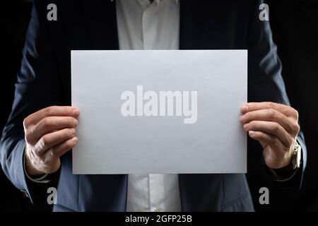 Ein Geschäftsmann hält ein leeres Papier vor sich. Stockfoto