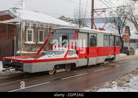 Alte rot-graue Reparatur-Straßenbahn KTM-5M3. Graues Stadtbild im Winter Stockfoto