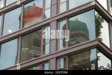 München, Deutschland. August 2021. Die beiden Türme der Frauenkirche spiegeln sich in den Fenstern eines Hochhauses in der Innenstadt wider. Kredit: Peter Kneffel/dpa/Alamy Live Nachrichten Stockfoto